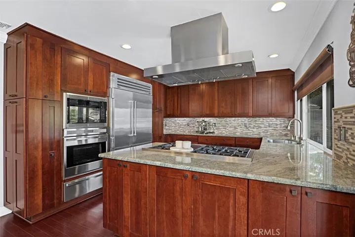 Designed for the serious home chef, this gourmet kitchen offers abundant cabinetry, expansive granite work surfaces, a built-in Sub-Zero refrigerator, Wolf dual-fuel professional range, double ovens, and a striking stainless steel hood.