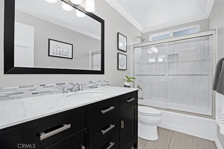 Updated secondary bathroom with quartz countertops, custom cabinetry, and a shower/tub combination finished with timeless tile surrounds.