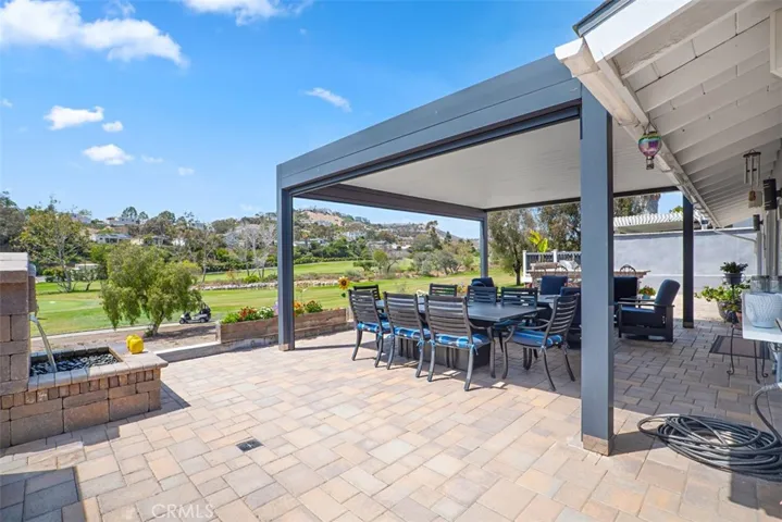 The expansive paver patio is designed for entertaining, featuring a tranquil built-in fountain, multiple gathering spaces, and panoramic views overlooking Shorecliffs Golf Club.