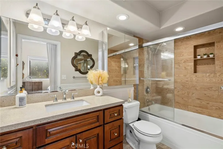 Primary bath with a dual-sink vanity, custom tile surround, and glass-enclosed shower/tub.