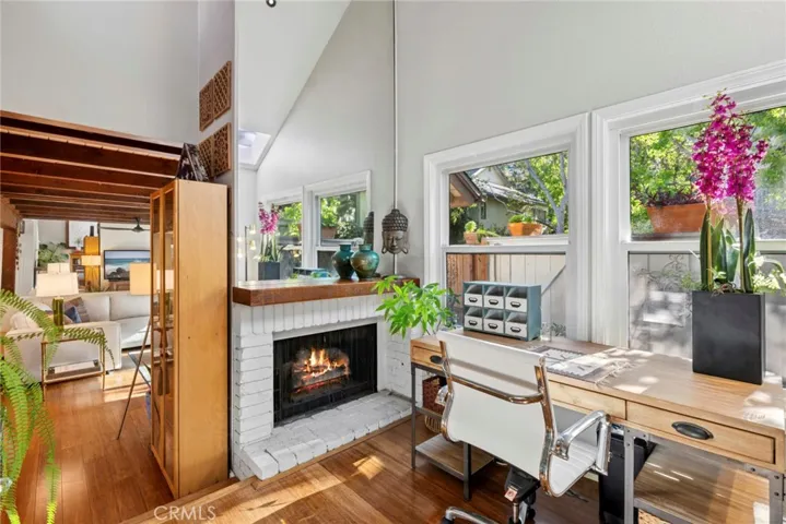 Natural light pours into this versatile flex space, where soaring ceilings, a fireplace, and views of the expanded rear patio create an inspiring place to work or read a book.