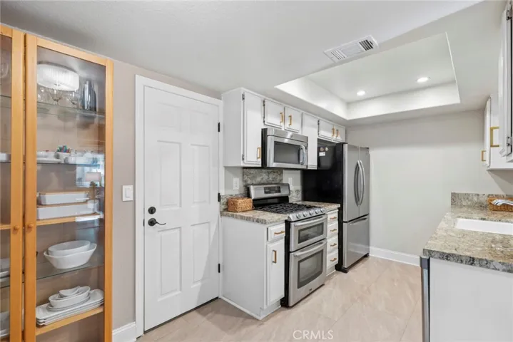 Granite countertops, stainless steel appliances, double oven, gas cooktop, and recessed lighting create a kitchen designed for everyday living.