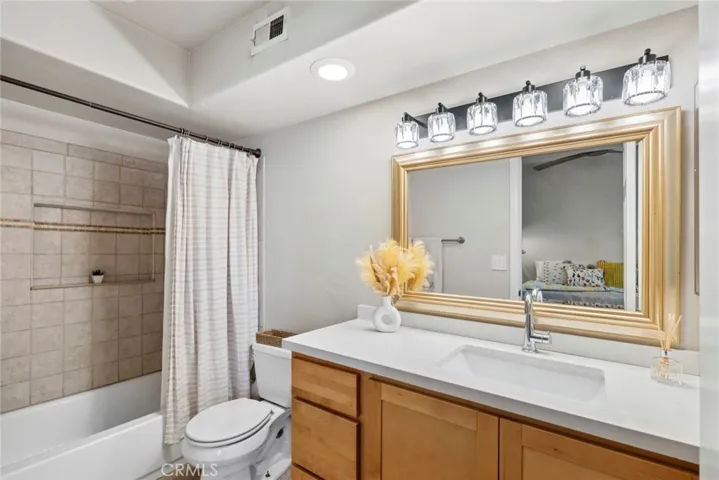 Updated ensuite bath with a quartz vanity, oversized shower/tub combination, and clean, modern finishes.