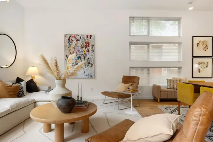 Spacious living area featuring high ceilings, light wood-finish flooring, and multiple horizontal windows