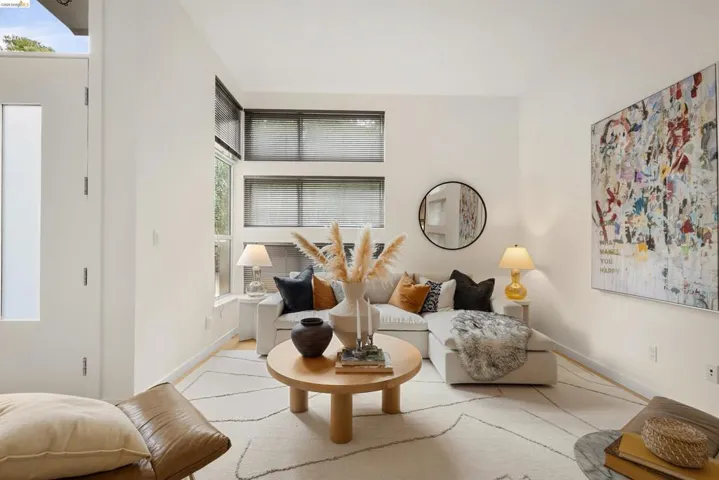 Living area featuring high ceilings, light wood-finish flooring, and multiple windows providing natural light