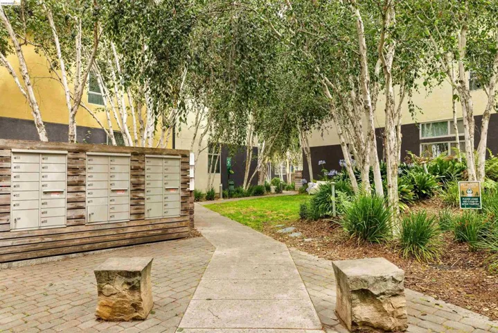 Community mailboxes with a wood-panel surround, set on a paver stone courtyard