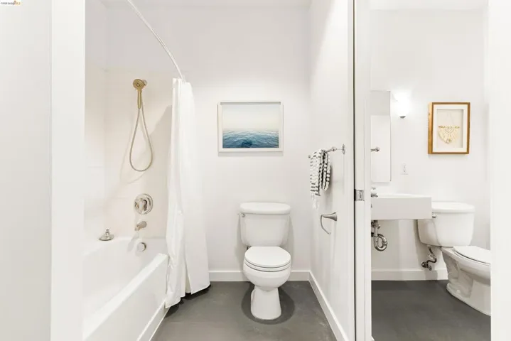 White-tiled bath and shower combination with a curved shower rod and handheld shower fixture