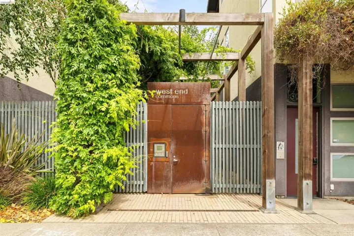 Entryway featuring a distressed metal door, vertical slatted fencing, and a wood pergola