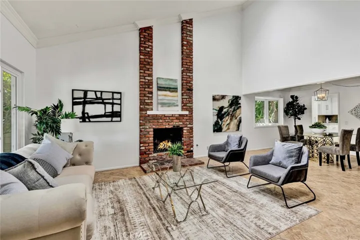 Formal living room filled with natural light, featuring vaulted ceilings and a cozy fireplace