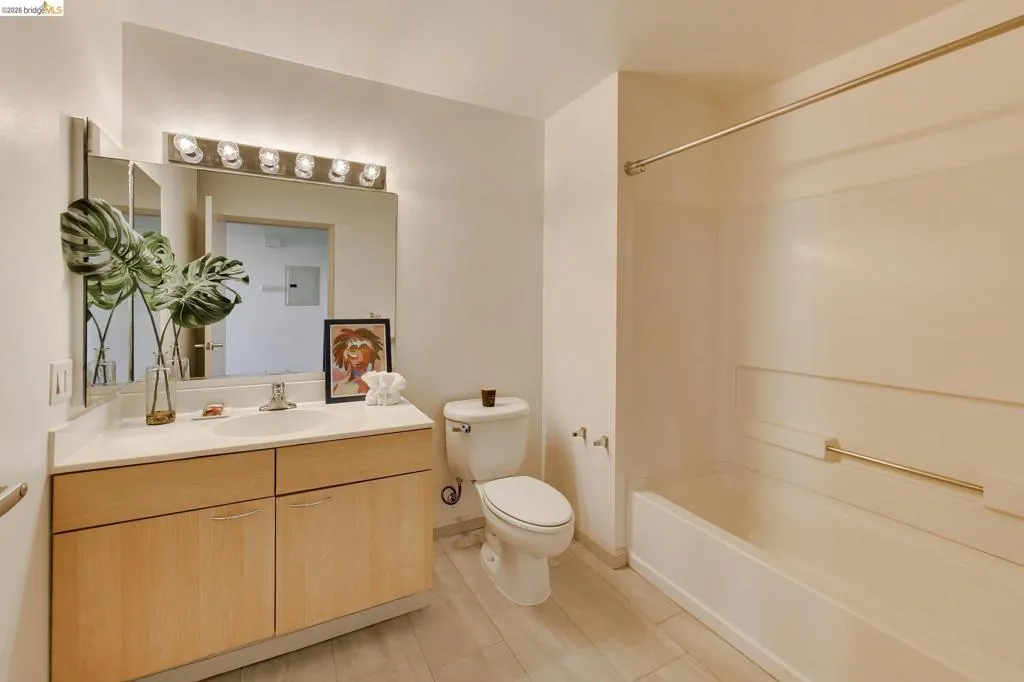 Bathroom featuring a wood-finish vanity with an integrated sink, a large mirror, and a five-light fixture