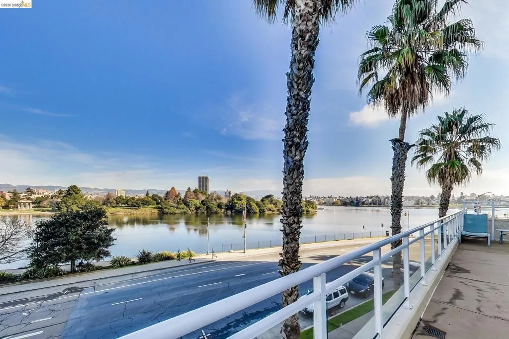 Expansive waterfront setting featuring a tranquil lake, distant city buildings, and lush parkland