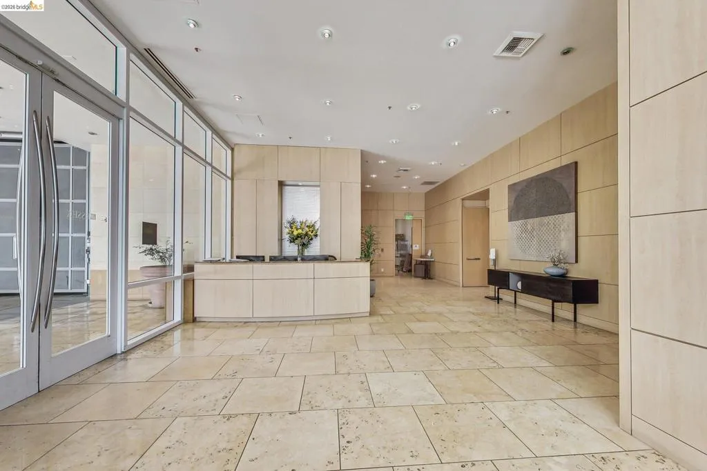 Spacious entry foyer featuring large format light-toned tile flooring, extensive wood paneling, and recessed lighting