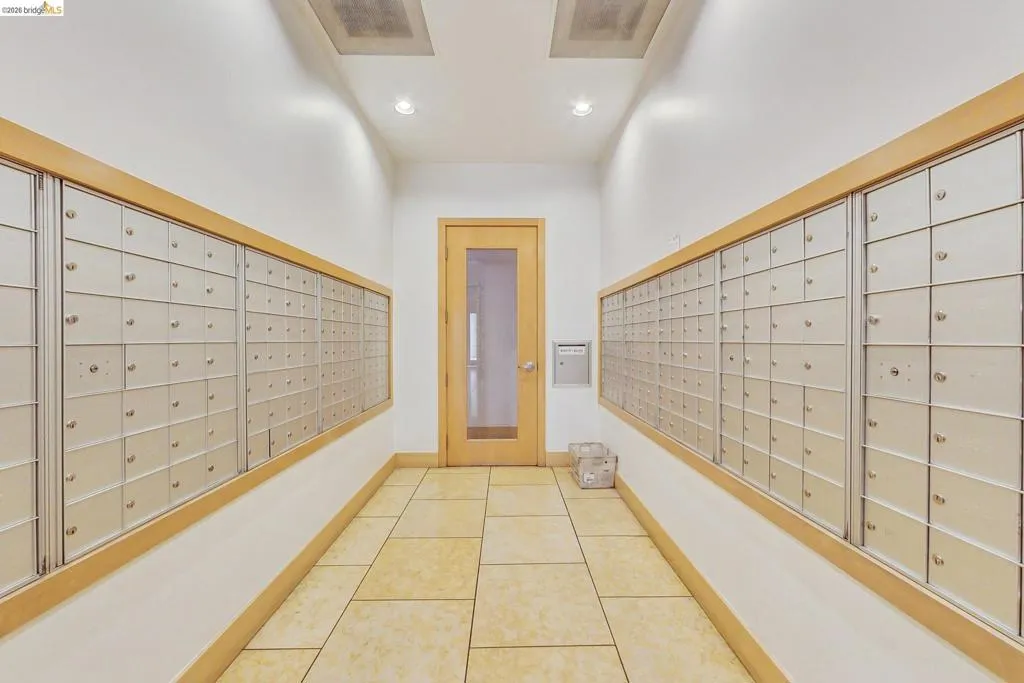 Corridor featuring wall-mounted mailboxes with wood trim, recessed lighting, and square tile flooring