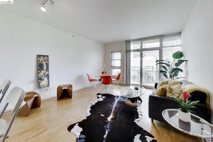 Open-concept living area featuring blonde wood-finish flooring, a full-height window wall, and a track lighting fixture