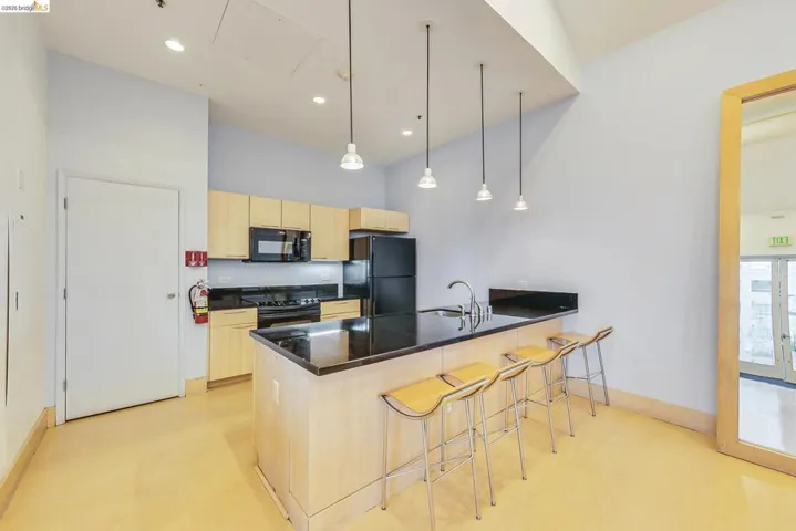 Kitchen featuring light wood cabinetry, black countertops, and stainless steel appliances