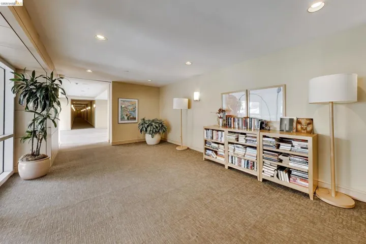 Carpeted communal area featuring recessed lighting, wall sconces, and built-in shelving units