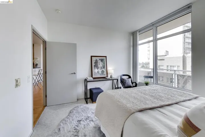 Expansive window wall with urban exposure, featuring a light-colored carpet, white walls, and a modern interior door with brushed metal hardware