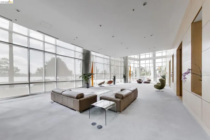 Curved window walls with roller shades and a recessed lighting array illuminate this spacious interior