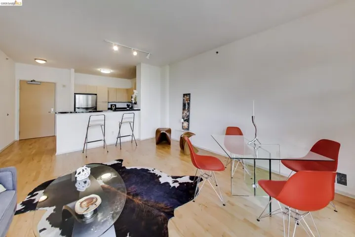 Open-concept living area with wood-finish flooring, a kitchen bar counter, integrated kitchen cabinetry, and track lighting