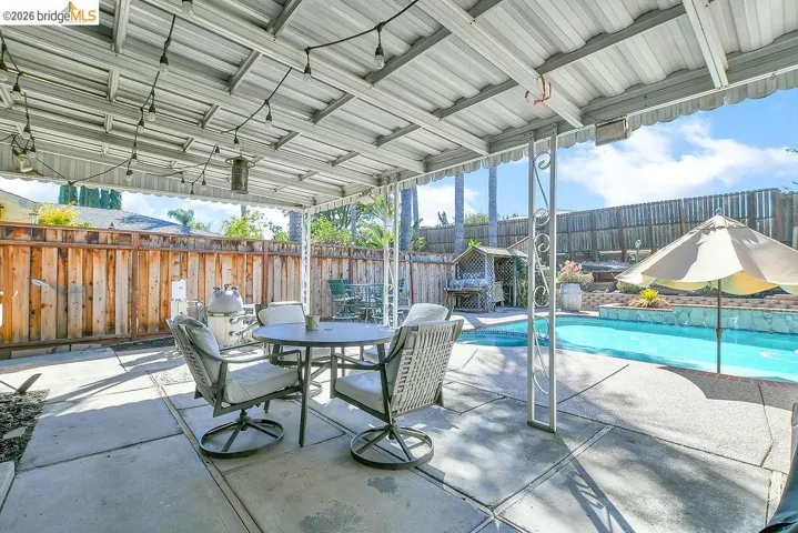 Covered patio with string lighting and concrete slab flooring