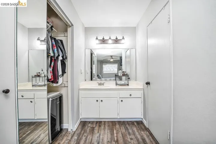 Vanity area featuring wood-finish flooring, a white vanity with a built-in sink, and a large mirror