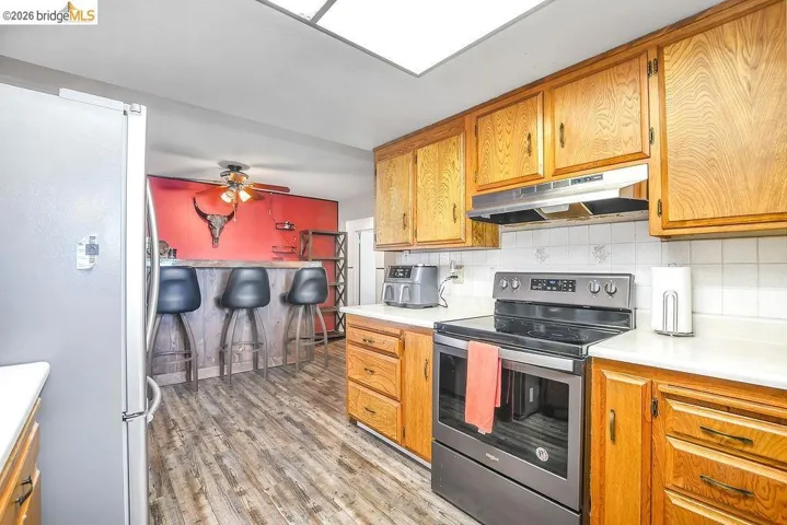Kitchen featuring wood cabinetry, white countertops, tile backsplash, and stainless steel appliances