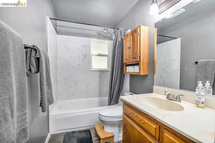Bathroom featuring a white bathtub, white vanity with integrated sink, wood-finish cabinetry, and a mirrored medicine cabinet