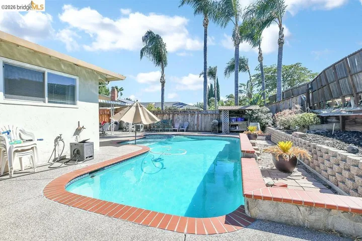 In-ground swimming pool with brick coping and surrounding aggregate concrete patio