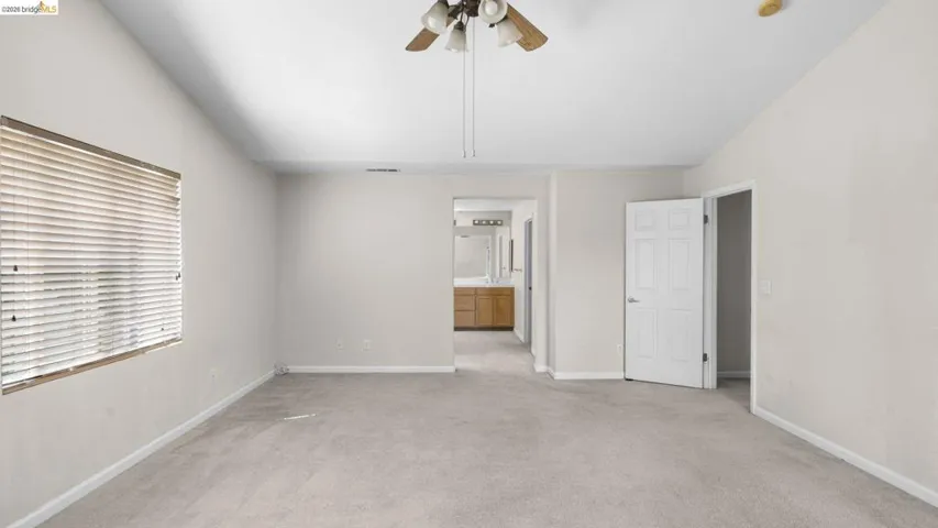 Spacious room featuring vaulted ceilings, light neutral wall paint, and beige carpeting