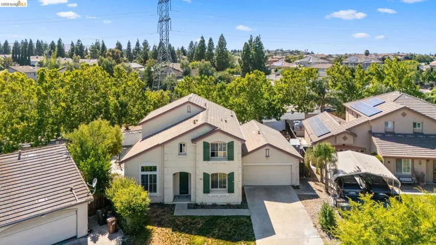 Two-story residence featuring a stucco exterior, green window shutters, and an arched entry