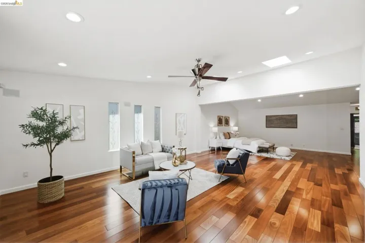 Open-concept interior featuring rich wood-finish flooring, vaulted ceilings, recessed lighting, a skylight, and transom windows