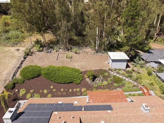 Expansive terraced yard featuring mature shrubbery, bark ground cover, and a detached shed
