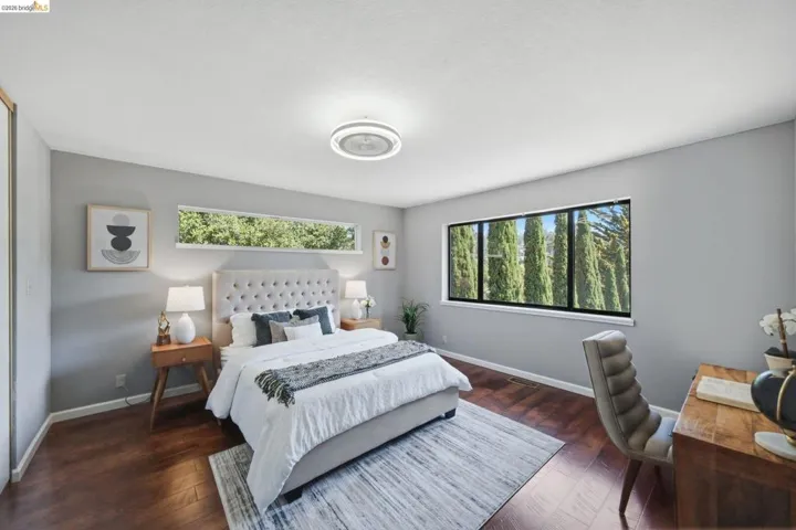 Spacious room featuring wood-finish flooring, a contemporary ceiling light fixture, and light gray wall paint