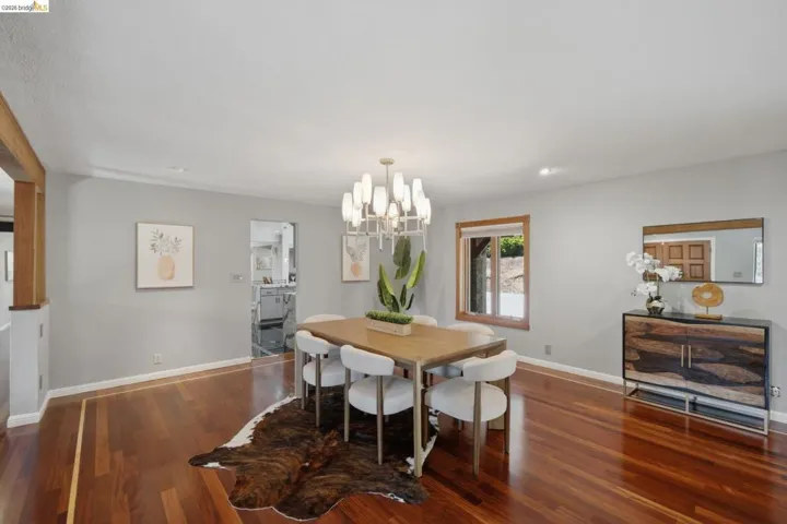 Spacious dining area featuring rich hardwood flooring with a distinct border inlay