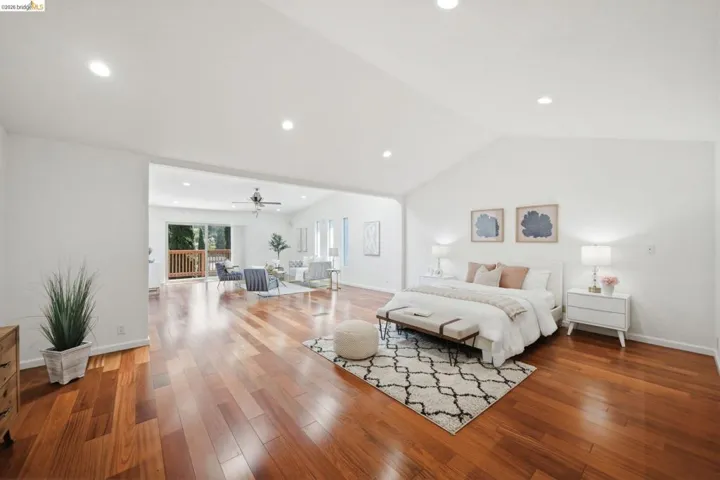 Vaulted ceiling bedroom featuring wood-finish flooring, recessed lighting, and a white color palette