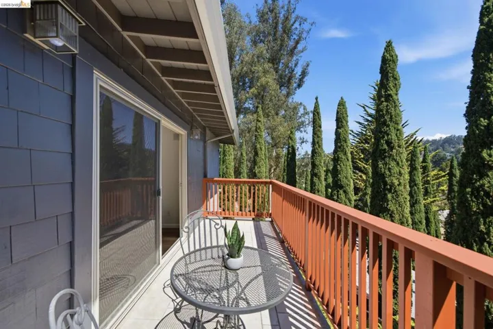 Private exterior balcony with a wood railing and a sliding glass door