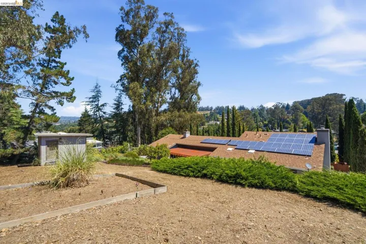 Property featuring a shingle roof, multiple solar panels, and two chimney stacks