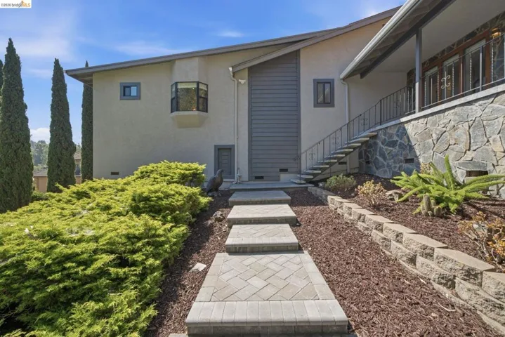 Entryway featuring paver steps and a stone veneer foundation