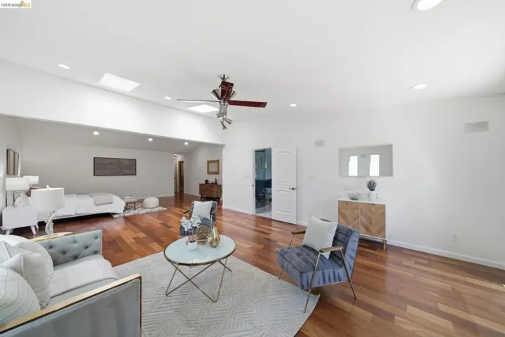 Spacious room featuring wood-finish flooring and a vaulted ceiling with skylights