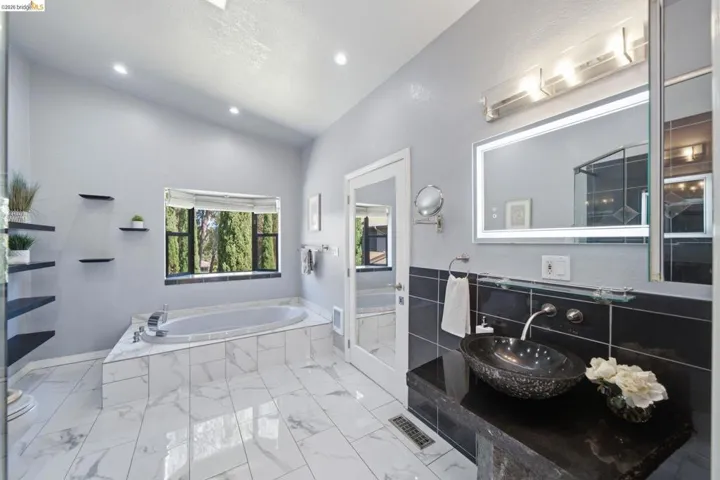 Spacious bathroom featuring a built-in soaking tub, large window, and recessed lighting