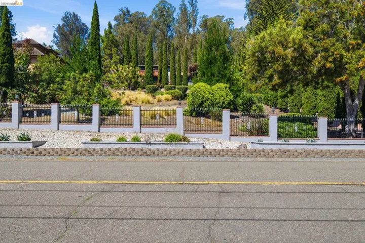 Street-level view featuring a decorative perimeter fence with stone pillars and black wrought iron sections
