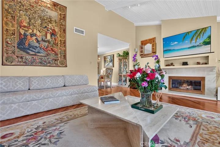 Vaulted living room with beamed ceiling and ceiling fan and fireplace