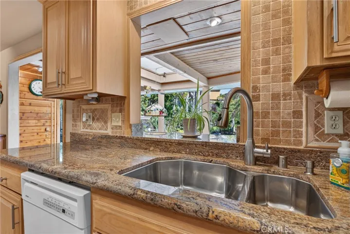 Beautiful wood cabinetry kitchen with granite countertops and mosaic backsplash, island with cooktop, stainless steel sinks, stainless steel ovens.