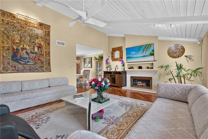 Vaulted living room with beamed ceiling and ceiling fan and fireplace