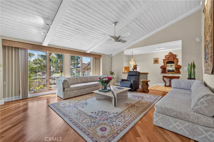 Vaulted living room with beamed ceiling and ceiling fan and fireplace