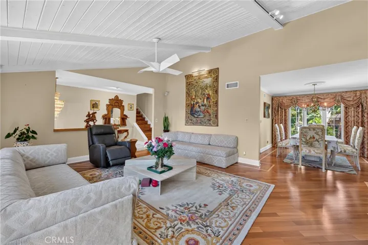 Vaulted living room with beamed ceiling and ceiling fan and fireplace