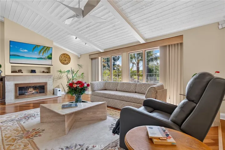 Vaulted living room with beamed ceiling and ceiling fan and fireplace