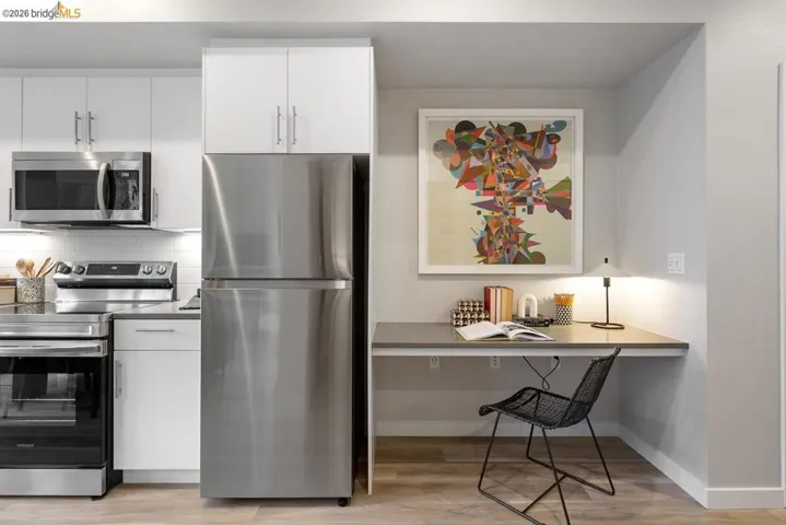 Efficient kitchen with stainless steel appliances, white cabinetry, and a dedicated desk area