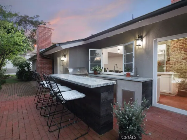 Built in BBQ, refrigerator, outdoor sink and dining area with passthrough window to the kitchen