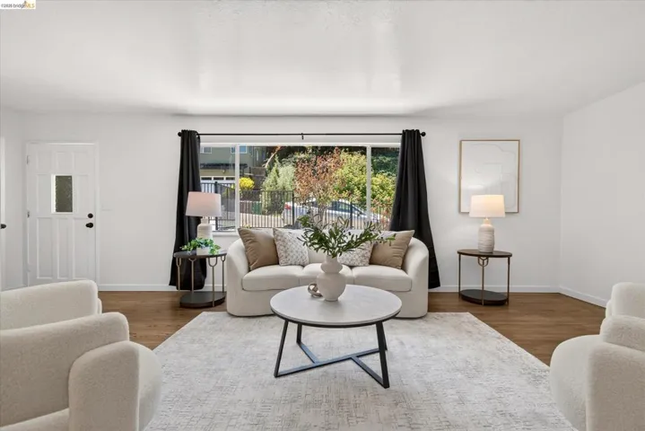 Living space featuring wood-finish flooring, white walls, and a large window with exterior views